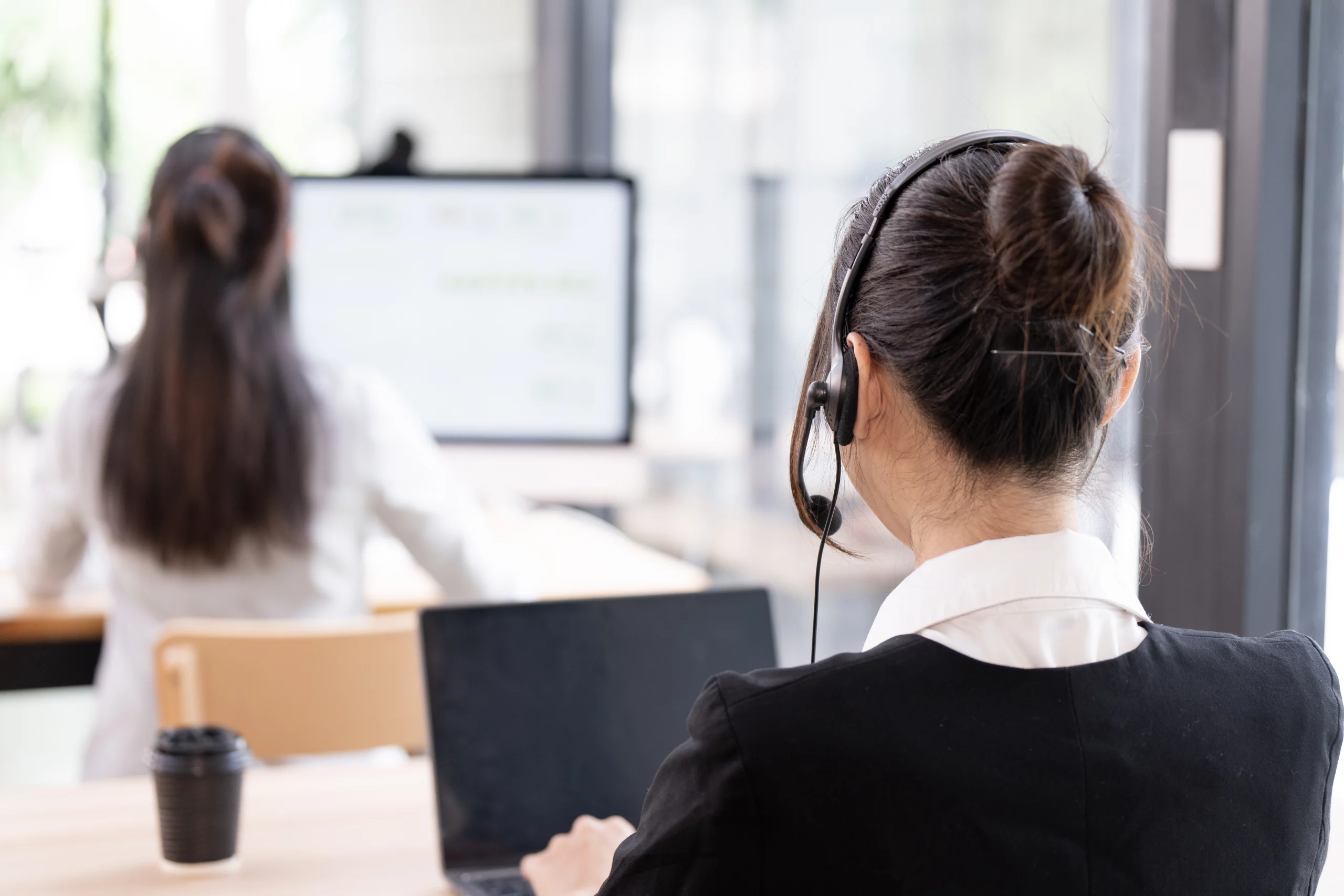 Rear view of woman call center with head set working in team off